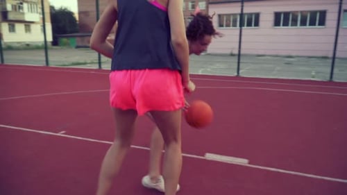 Two Young Women Play Basketball Outside