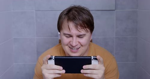 Intense Gaming on Handheld Console in Bathroom