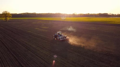 Tractor Working in Field at Sunset