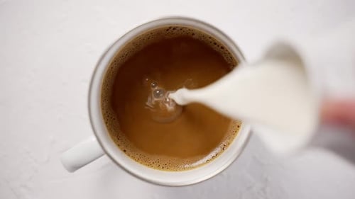 Milk Poured Into Coffee Mug in Slow Motion