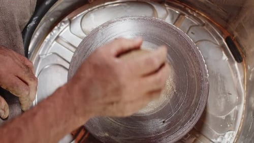 Potter met un morceau d'argile traitée sur le tour de potier propre d'une main et le gifle à la surface