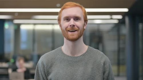 Cheerful Red-Haired Man Talking in Modern Workplace