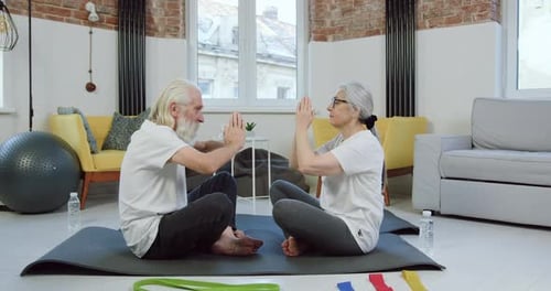 Senior Couple Practicing Yoga Exercises Together at Home