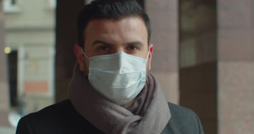 Close Up Portrait of Handsome Male in Medical Mask Standing Outdoors on Street and Looking at Camera