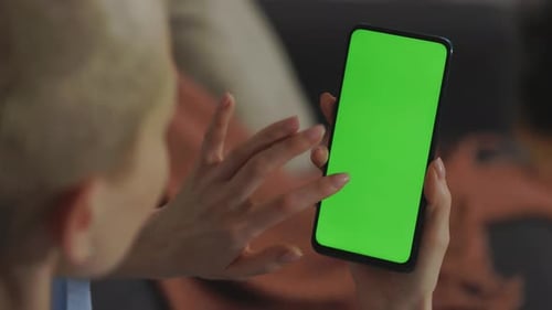 Woman Tapping Finger on Green Screen of Smartphone at Home