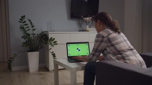 Side Moving Camera Freelancer Using Laptop with Green Screen Indoors