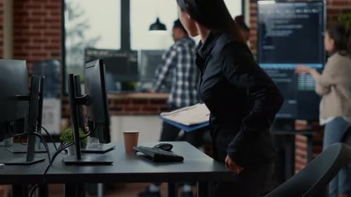 Asian Software Developer Holding Clipboard Sitting Down and Starting to Type