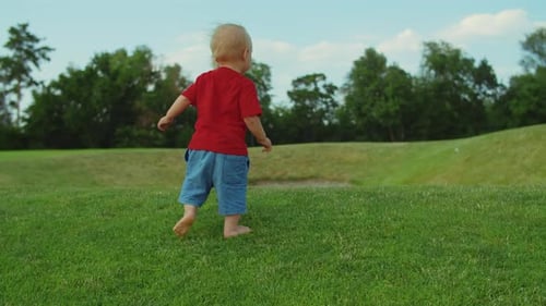 Toddler Running on Green Grass. Blonde Child Playing in Summer Park