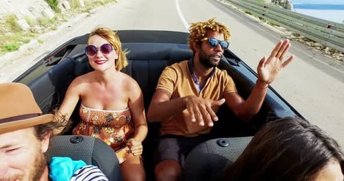 Blonde woman and black man riding in the back of convertible, color graded