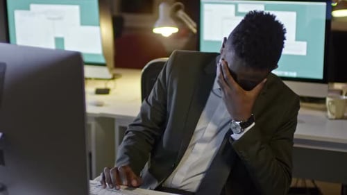 Sleepy Office Worker Typing on Computer at Night