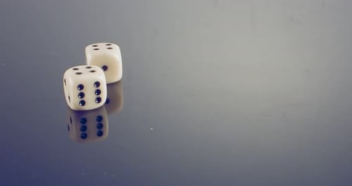 Imagen macro a cámara lenta de dados blancos cayendo y rodando sobre una superficie reflectante