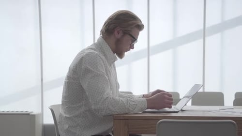 Young Adult Using Laptop in Bright Workplace