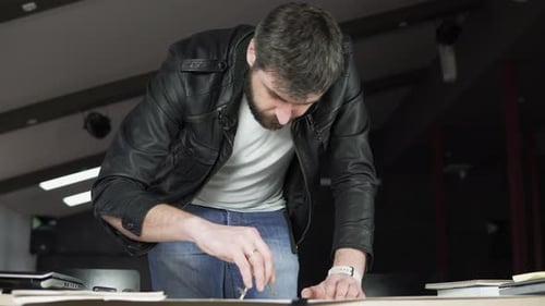 Young Man Working on a Project Drawing and Thinking in Modern Office