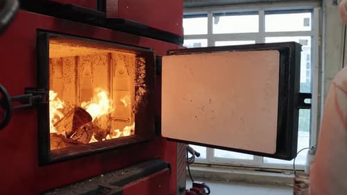 Man Adding Wood to Industrial Furnace