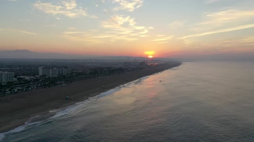 4k Ariel drone shot of the cityscape, beachfront hotels, and beach front homes at sunrise/sunset in