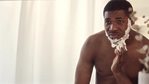 Man Applying Shaving Cream in a Bright Bathroom