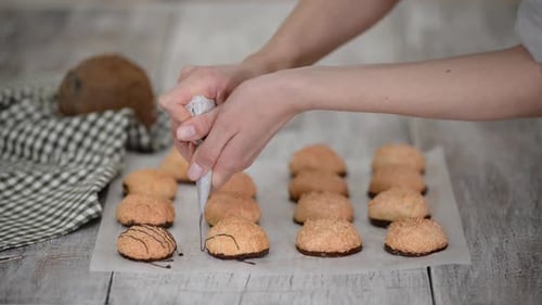 Se vierte salsa de chocolate sobre macarrones de coco en papel pergamino
