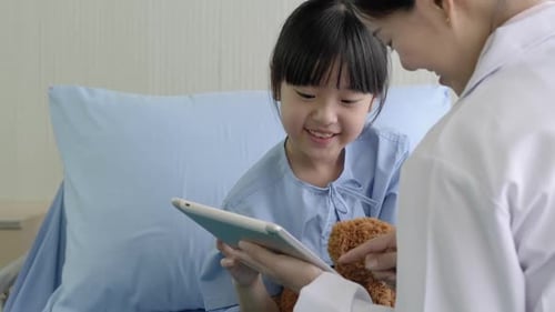 Child and Doctor Look at Tablet in Hospital