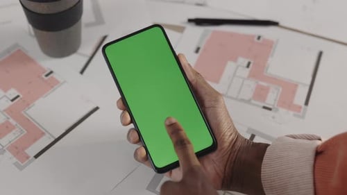 Male Architect or Designer Tapping Smartphone with Green Screen Mockup Chroma Key at Workplace Top
