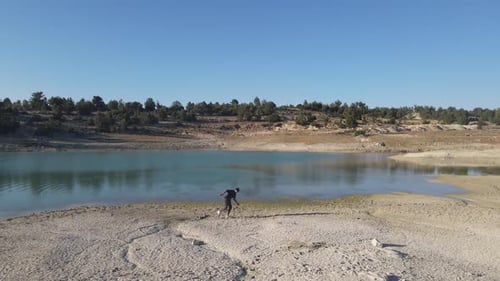Person Skipping Stones Into Remote Lake, Aerial View
