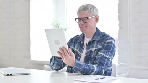 Fleißiger, lässiger Mann mittleren Alters mit Tablet