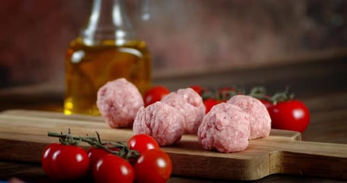 Arranging Raw Meatballs on Cutting Board with Tomatoes