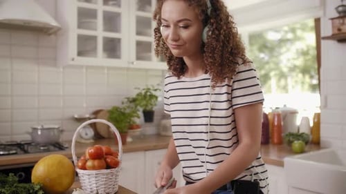Woman Chopping Vegetables and Listening to Music