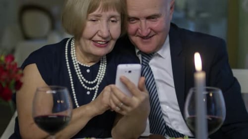 Senior Couple with Mobile Phone in Restaurant