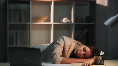 Tired Woman Sleeping at Desk in Office