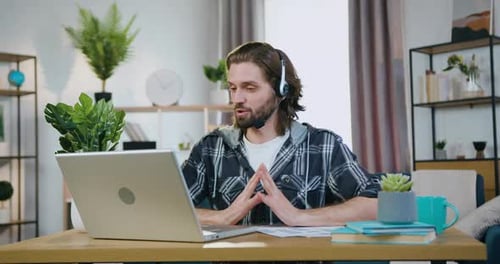 Office Worker in Headphones Holding Video Meeting with Coworkers from Home Office