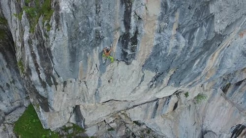Aerial drone view of a man rock climbing up a mountain