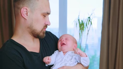 Father Holding Crying Newborn Baby Indoors