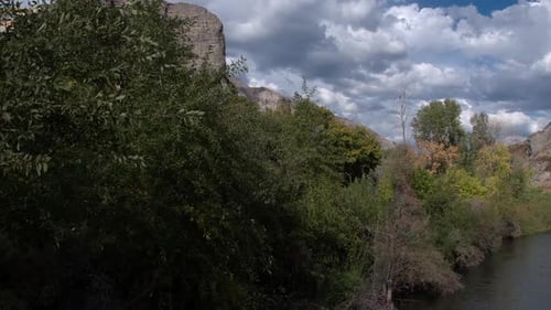 Flug über Fluss und Bäume in Richtung felsiger Klippe