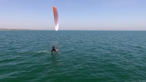 Kiteboarder Gliding Across Open Water on Sunny Day