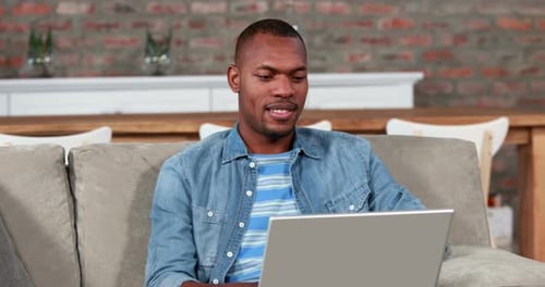 Man Using Laptop Smiling on Comfortable Couch