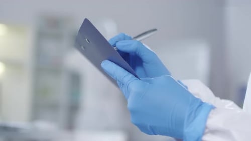 Scientist in Lab Writing on Clipboard