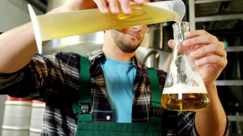 Brewer pouring beer in laboratory flask 4k