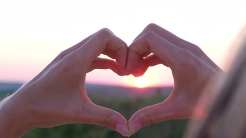 Hands Make Heart Shape at Picturesque Sunset