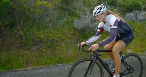 Female cyclist cycling on a countryside road 4k