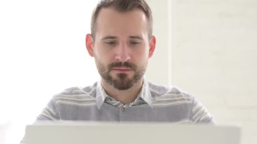 Adult Man Smiling at Laptop Screen, Close Up
