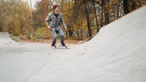 Skater Practicing in the Autumn Concrete Skate Park Making Tricks and Rides in Ramp