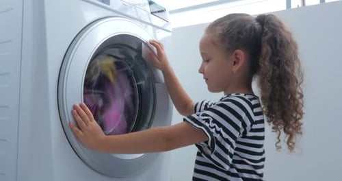 Nettes Kind schaut in die Waschmaschine