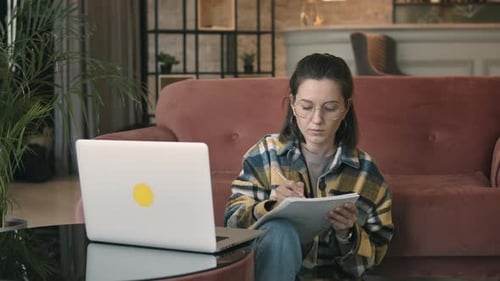 Woman Working on Laptop at Home Making Notes