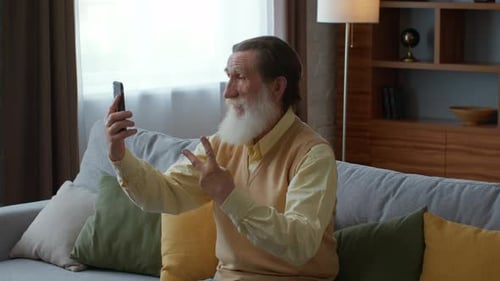 Senior Man Video Calling From Sofa At Home
