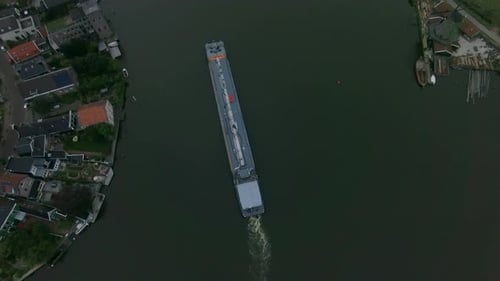 Aerial shot of barge sailing down the river in town