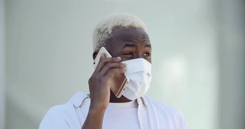 Porträt eines fröhlichen jungen afroamerikanischen Mannes im Freizeithemd in medizinischer Schutzmaske