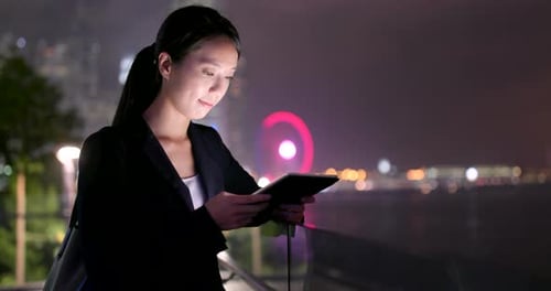Woman Using Tablet Device at Night in City