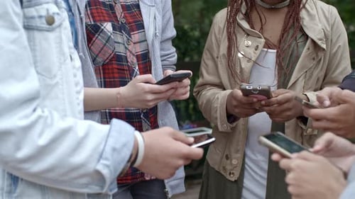 Group of Young Adults Using Mobile Phones Together