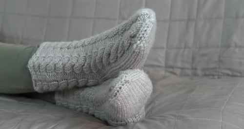 Relaxing Feet in Cozy Knitted Socks on Sofa