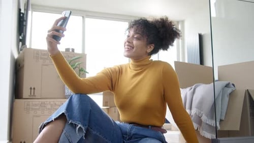 Woman Video Chats Amongst Moving Boxes in Apartment